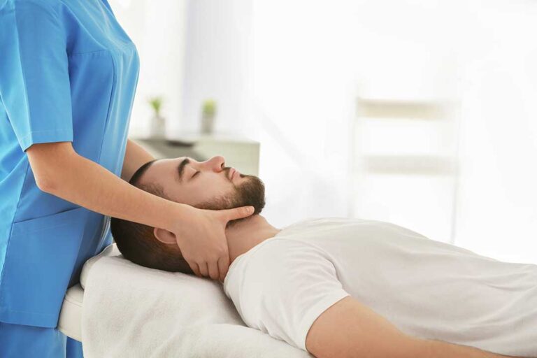 An adult using the log roll technique to rise from a bed in a sunlit bedroom, hands supporting the bedside.
