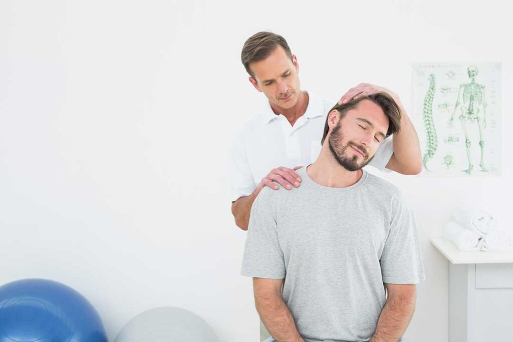 Person receiving a gentle back adjustment in a bright clinical room while discussing mobility with a practitioner
