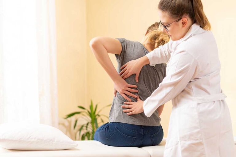 A chiropractor gently assessing a middle-aged person's back in a calm, professional clinical setting.