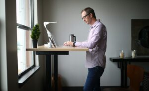 Person taking a brief walking break beside a comfortable computer workstation with relaxed posture.